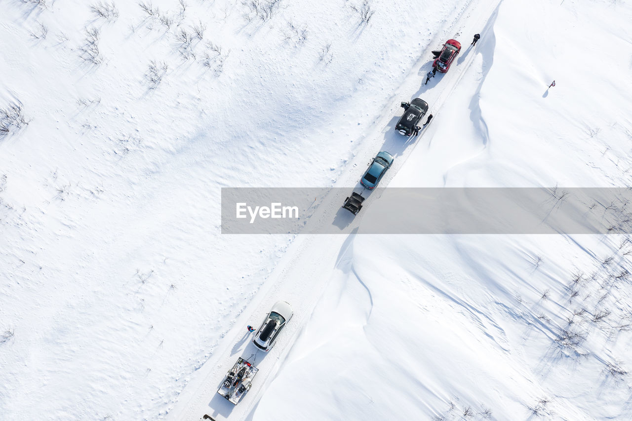 HIGH ANGLE VIEW OF PEOPLE SKIING ON SNOW COVERED LAND