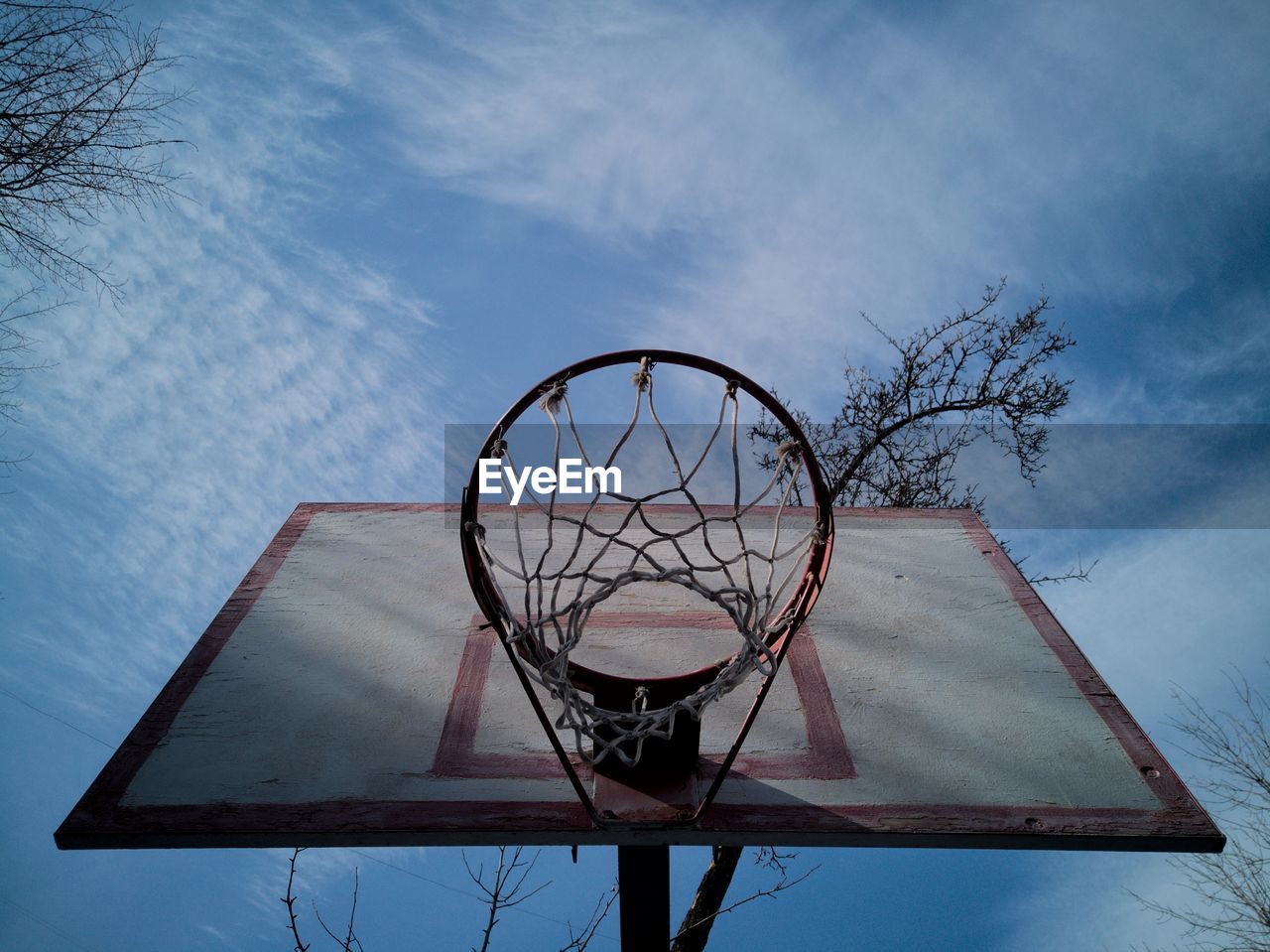 Directly below shot of basketball hoop against cloudy sky