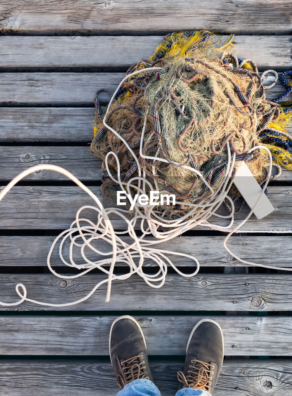 Low section of man by fishing net on boardwalk