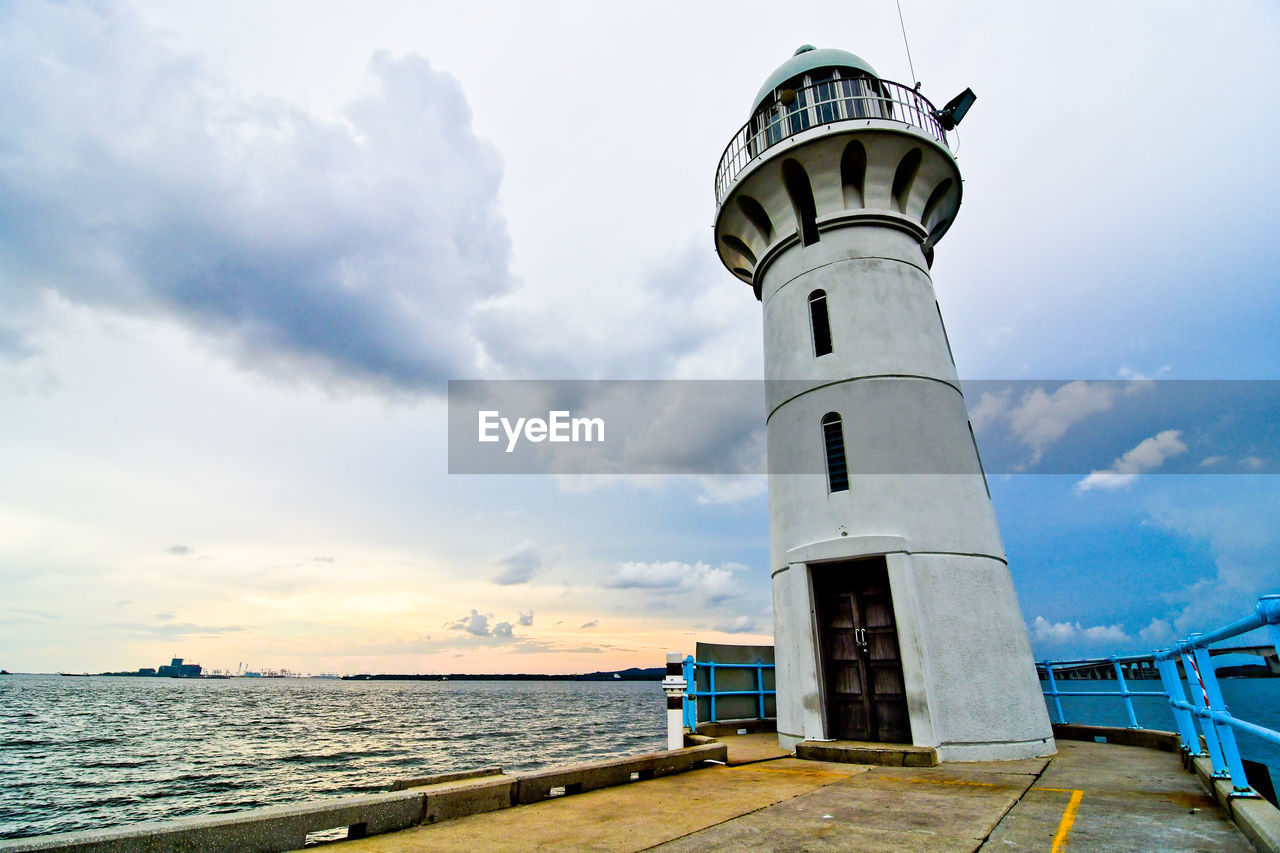 Lighthouse by sea against sky