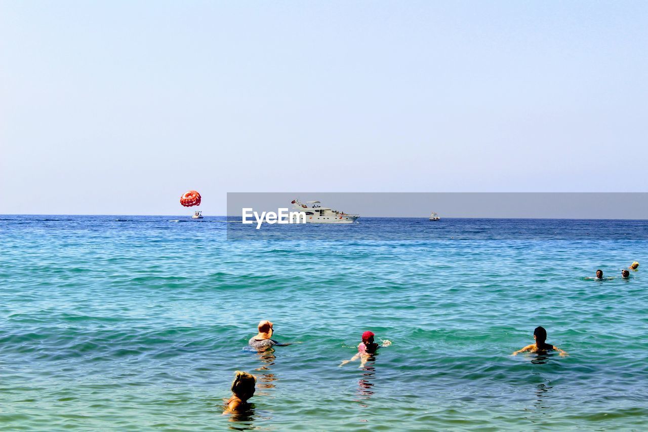 VIEW OF PEOPLE ON BEACH AGAINST CLEAR SKY