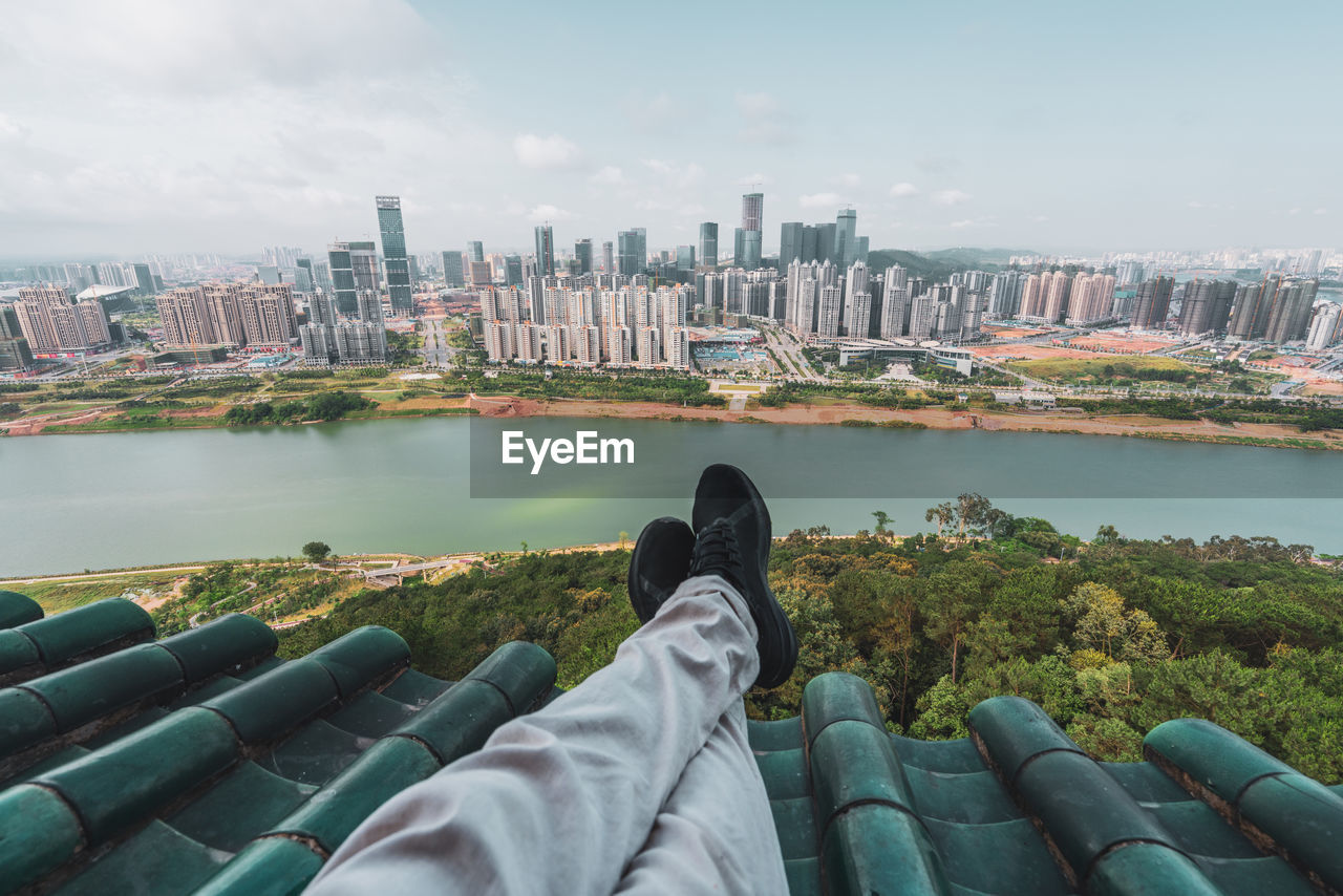 Crop tourist on rooftop with cityscape