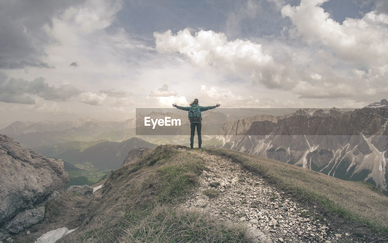 REAR VIEW OF MAN STANDING ON MOUNTAIN