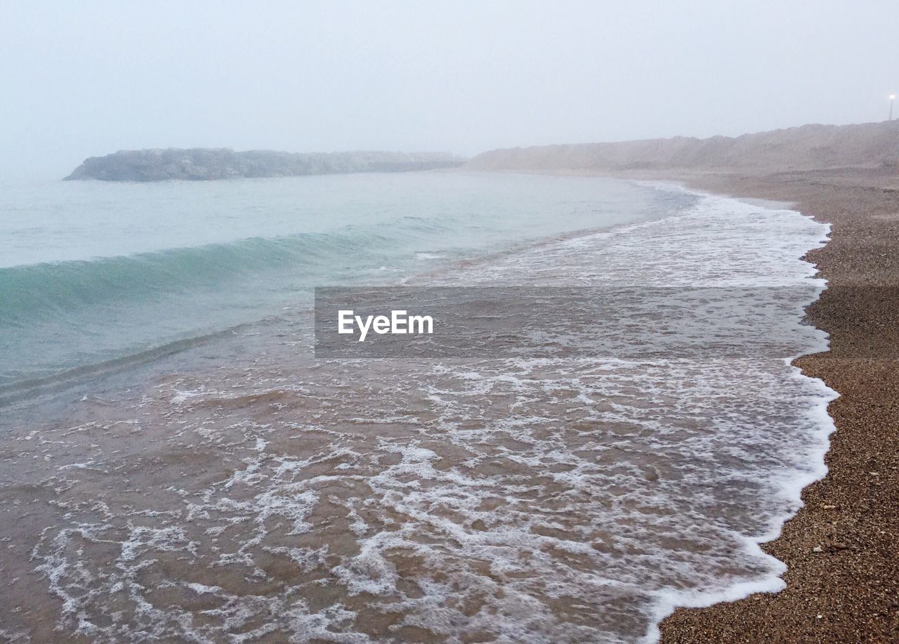 Scenic view of beach against cloudy sky