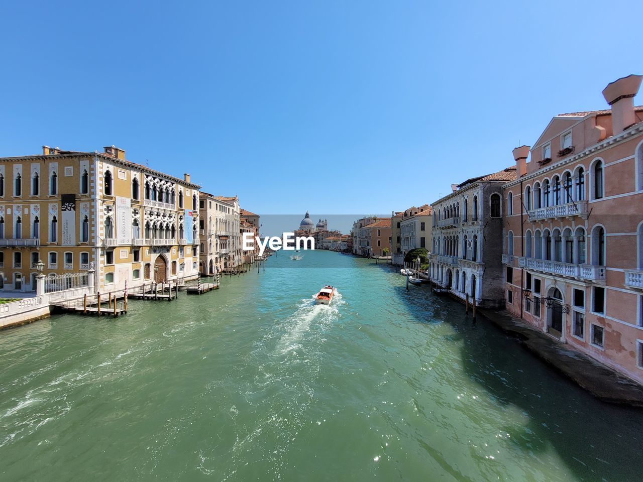 canal amidst buildings against clear blue sky