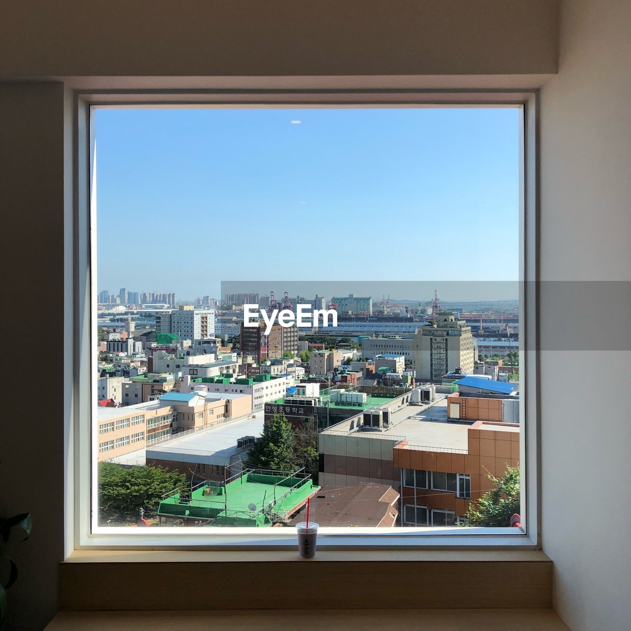 HIGH ANGLE VIEW OF BUILDINGS AGAINST CLEAR SKY SEEN THROUGH WINDOW