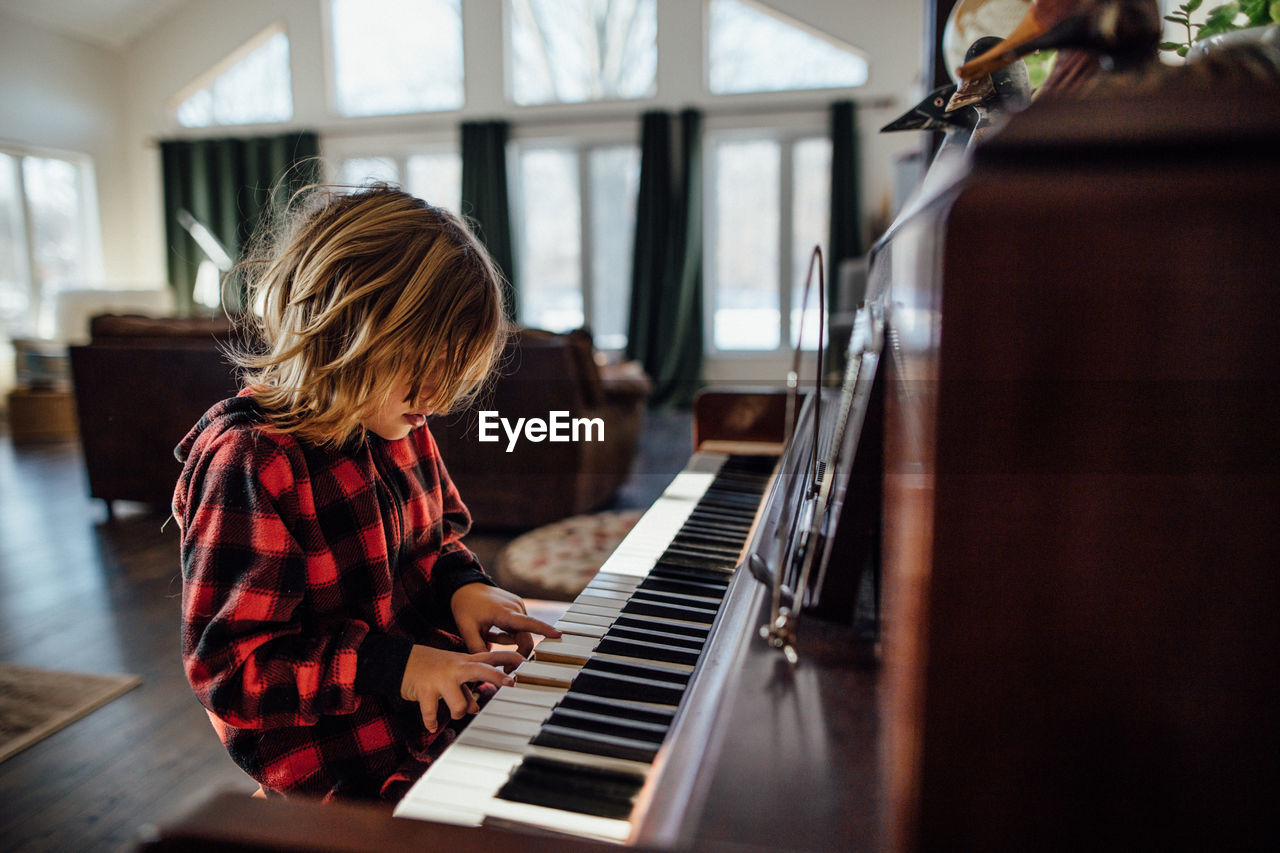 Little boy with messy hair playing the piano