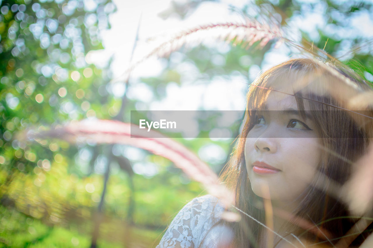 Young woman looking away by plants