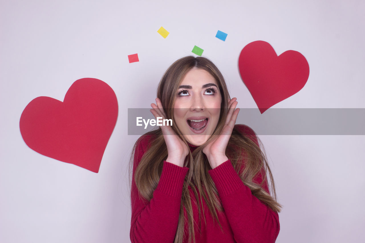 Screaming happy woman with heart shape against gray background