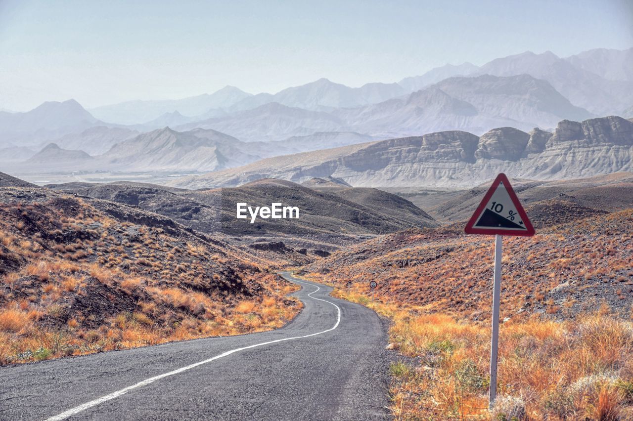 View of road leading towards mountains against sky