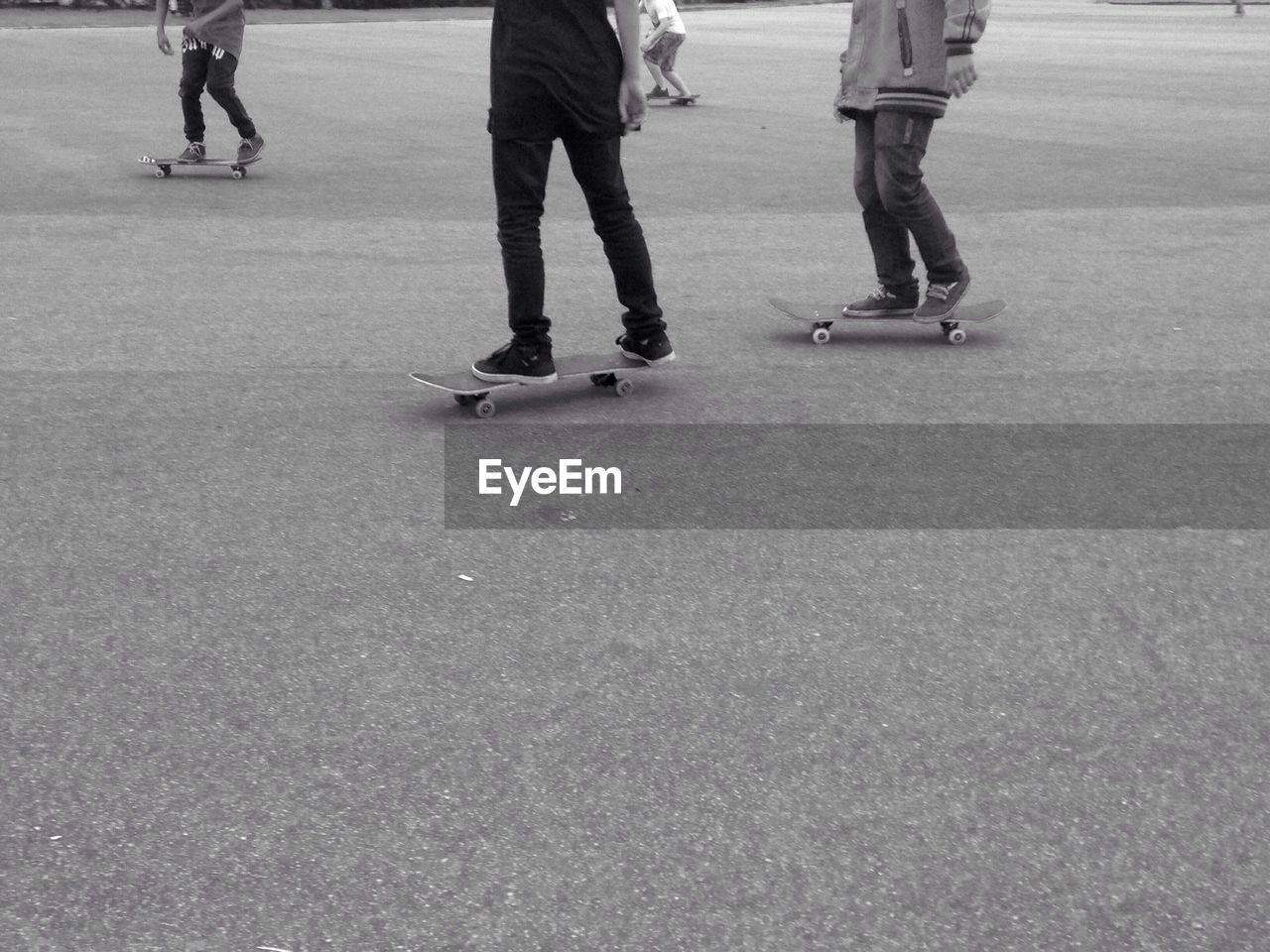 Low section of people skateboarding on road