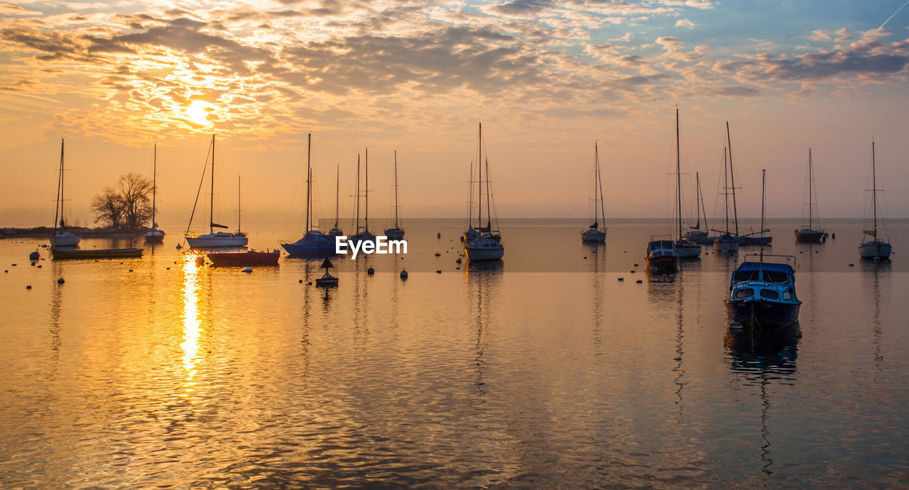 Boats moored in lake geneva against sky during sunset