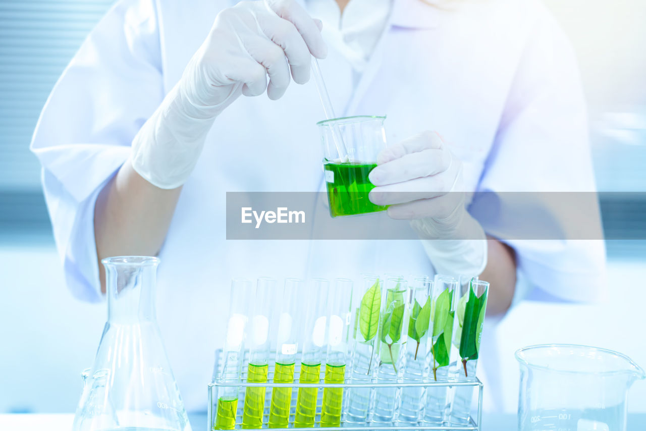 Midsection of scientist examining chemical in laboratory