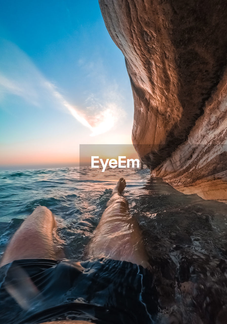 A man lies in the water under white rocks in abkhazia at sunset