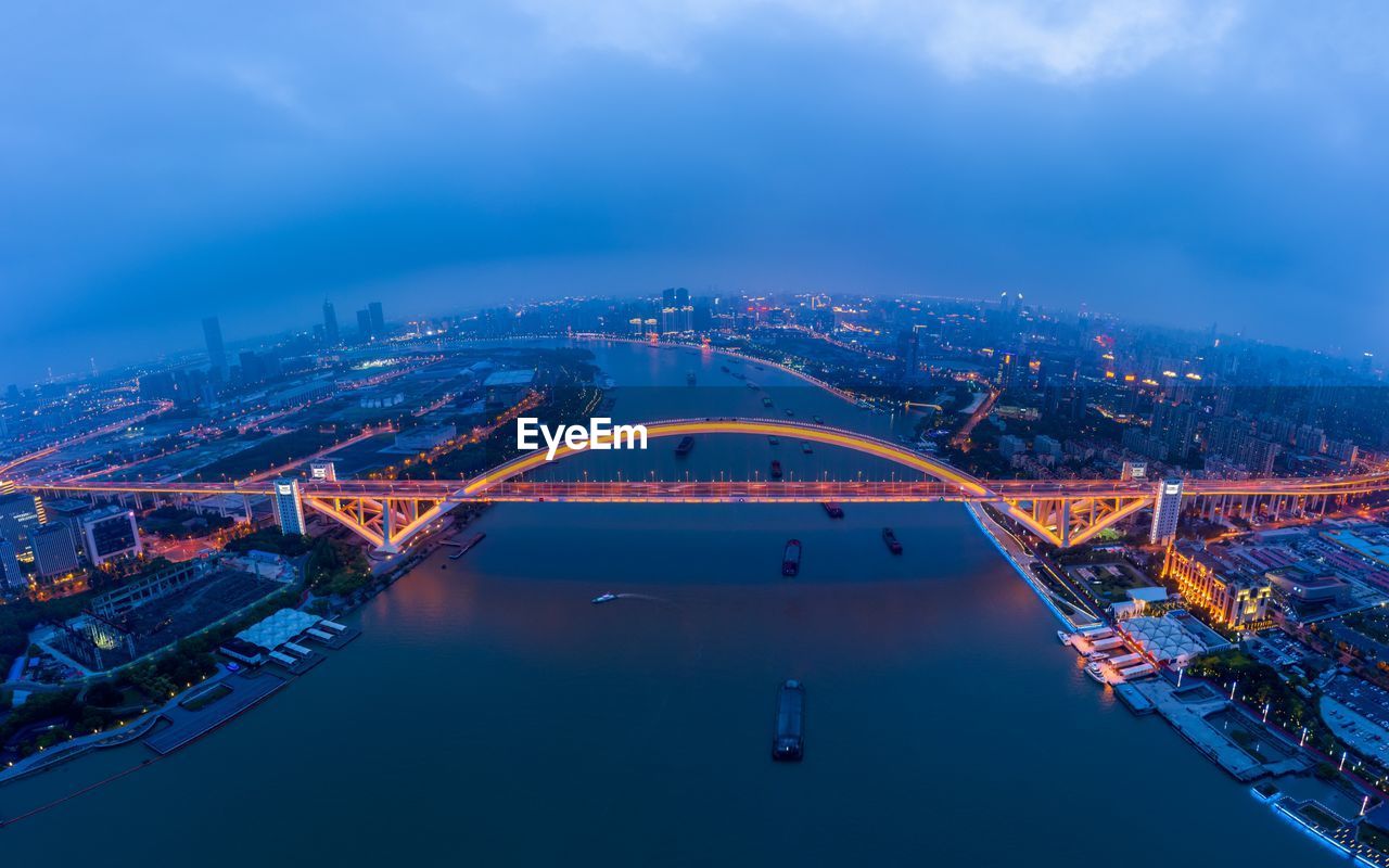 Aerial view of illuminated bridge over river at dusk