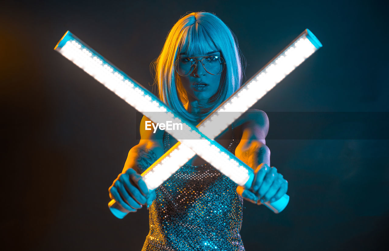 Woman in dress dancing with illuminated lights against black background