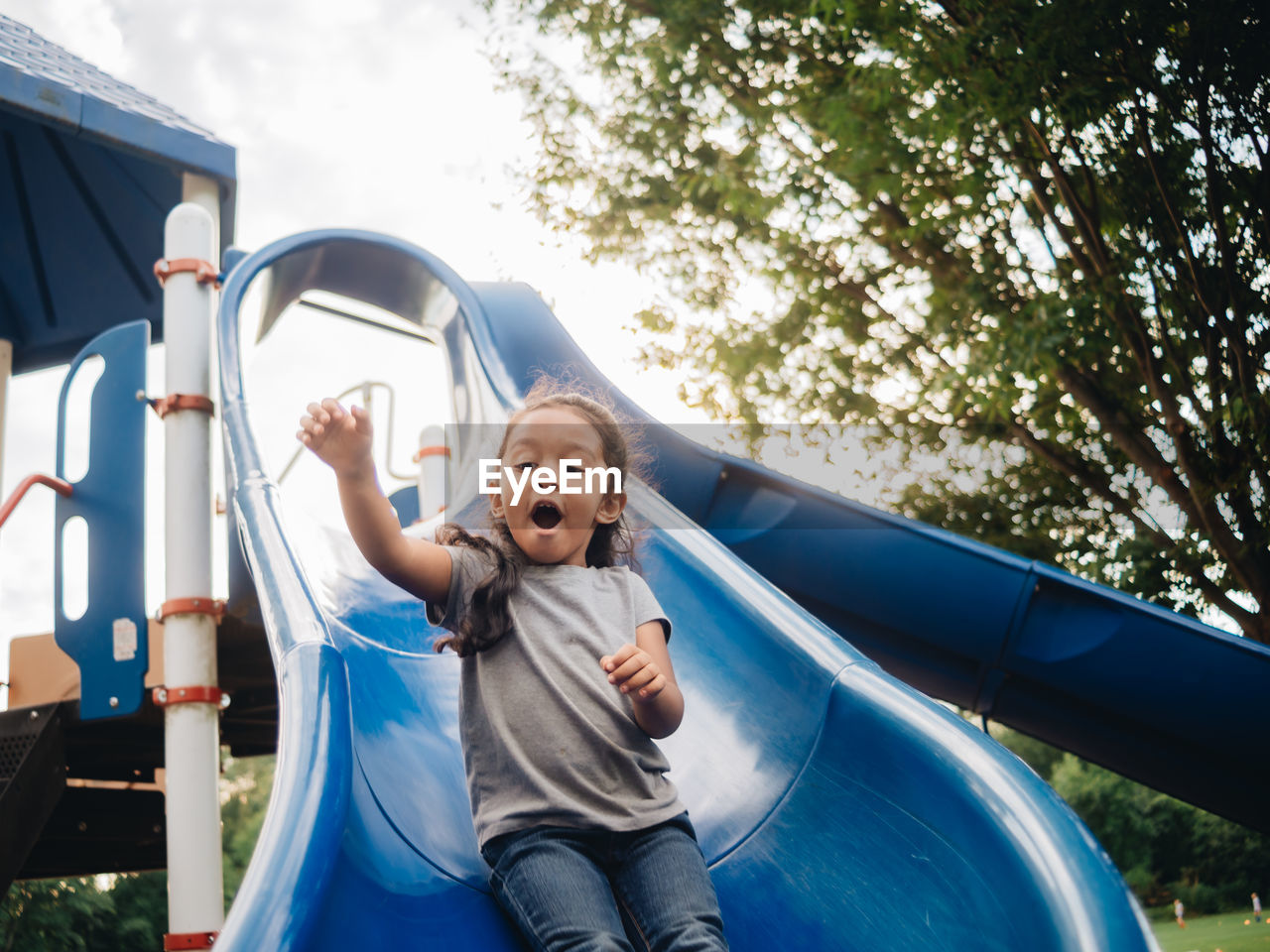 Cute girl standing on slide at park