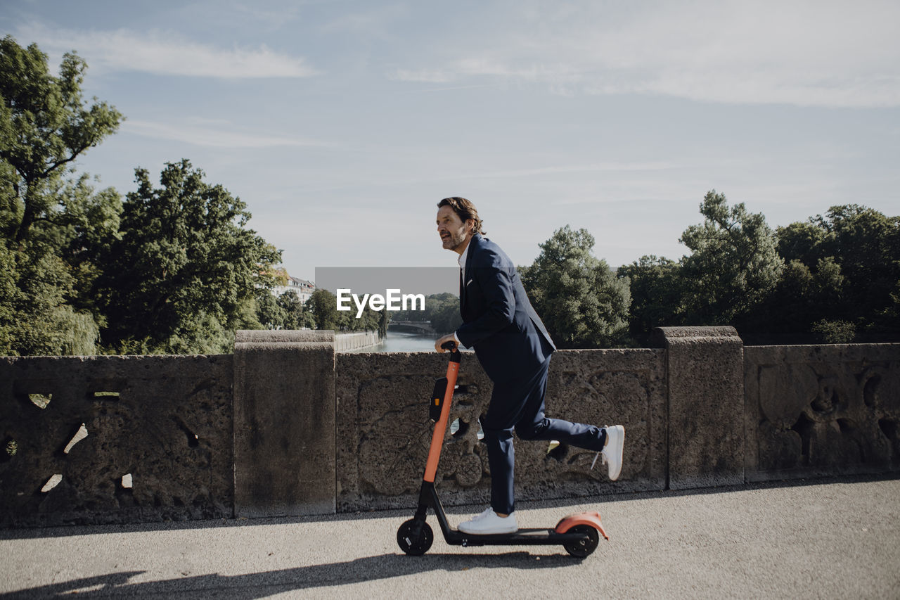 Businessman with e-scooter on a bridge