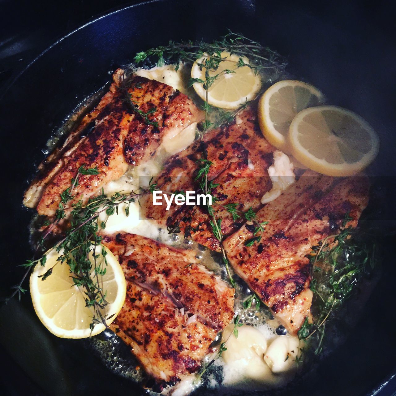 Close-up of fish cooking in pot with herbs and lemon