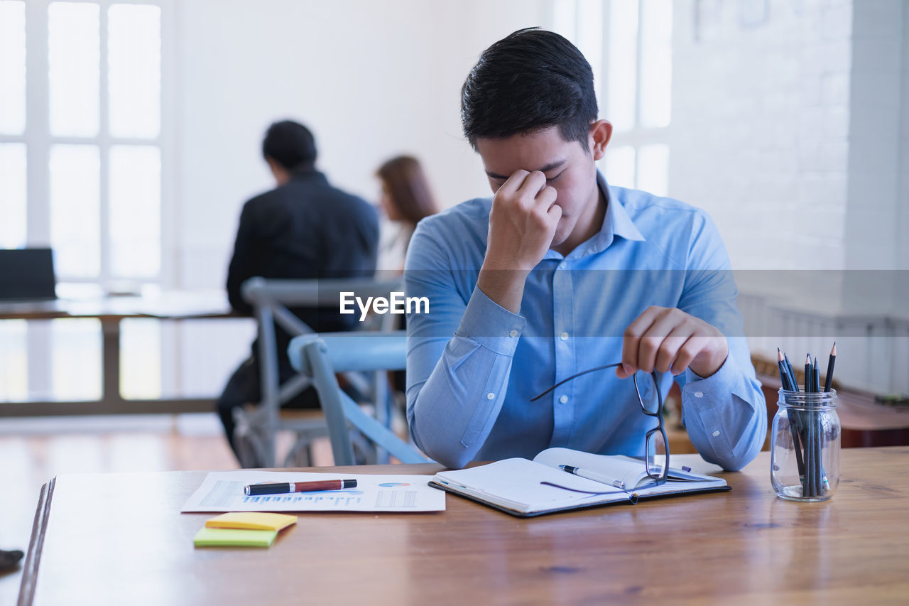 MAN USING MOBILE PHONE WHILE SITTING AT TABLE