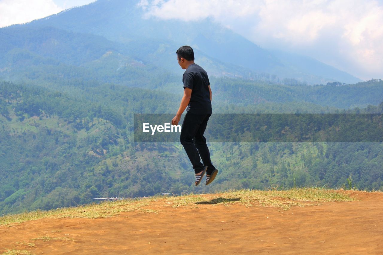 WOMAN STANDING ON MOUNTAIN LANDSCAPE