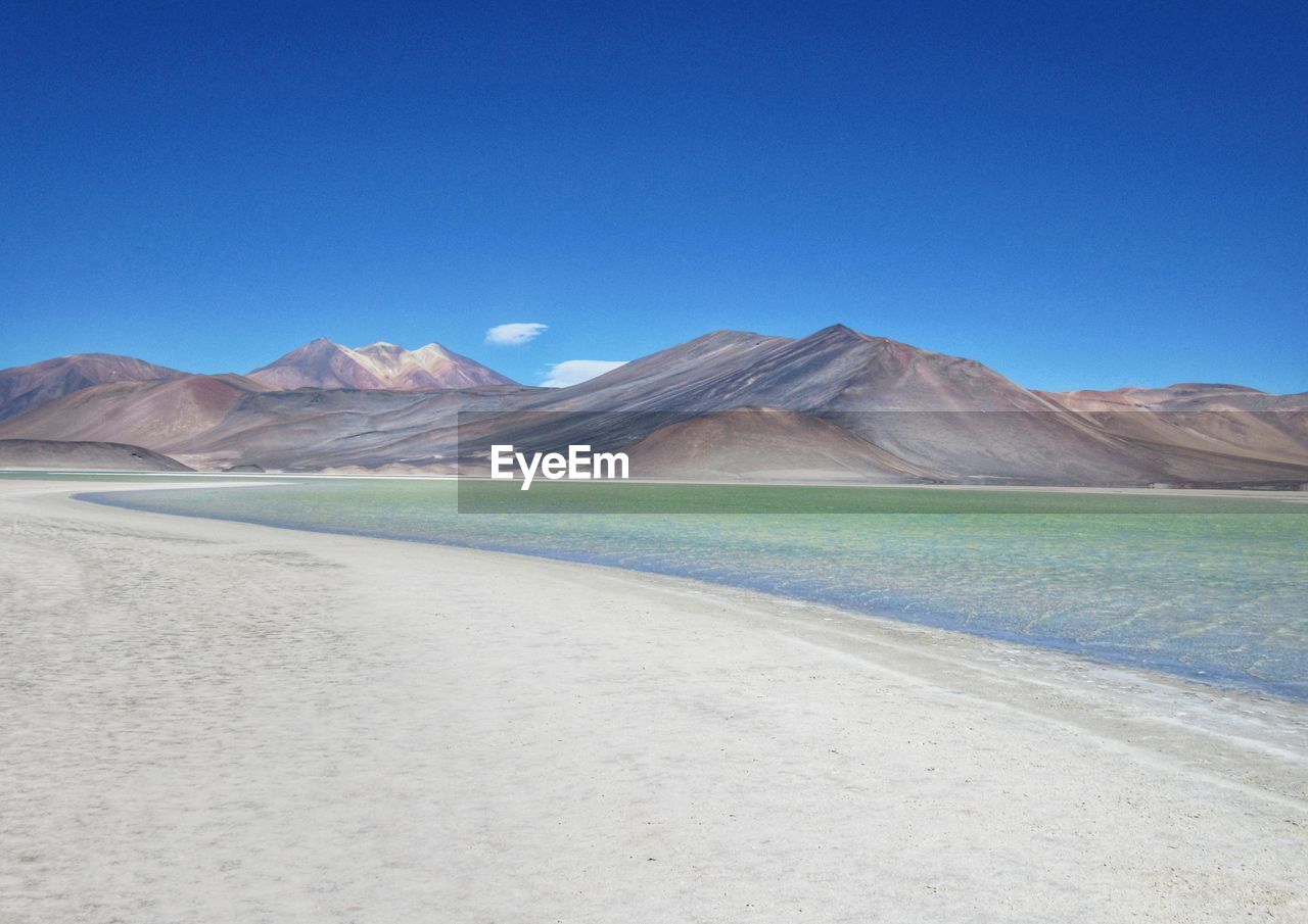 Scenic view of mountains against clear blue sky and blue lake 