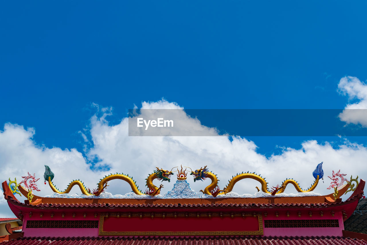 Low angle view of dragons against cloudy sky