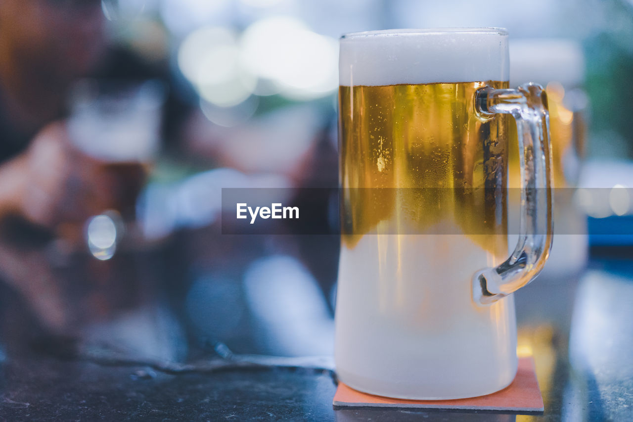 CLOSE-UP OF BEER GLASS ON WOODEN TABLE