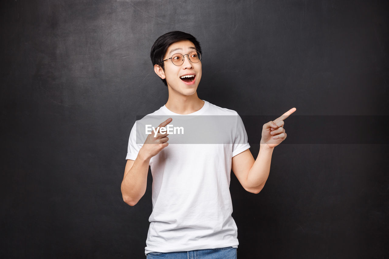 Portrait of young man gesturing against black background