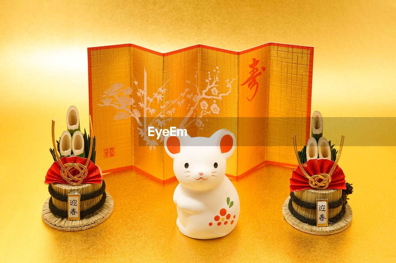 celebration, colored background, mammal, representation, yellow, no people, animal, holiday, animal representation, tradition, indoors, animal themes, studio shot, gold, decoration, craft, chinese new year, figurine, culture, event, festival