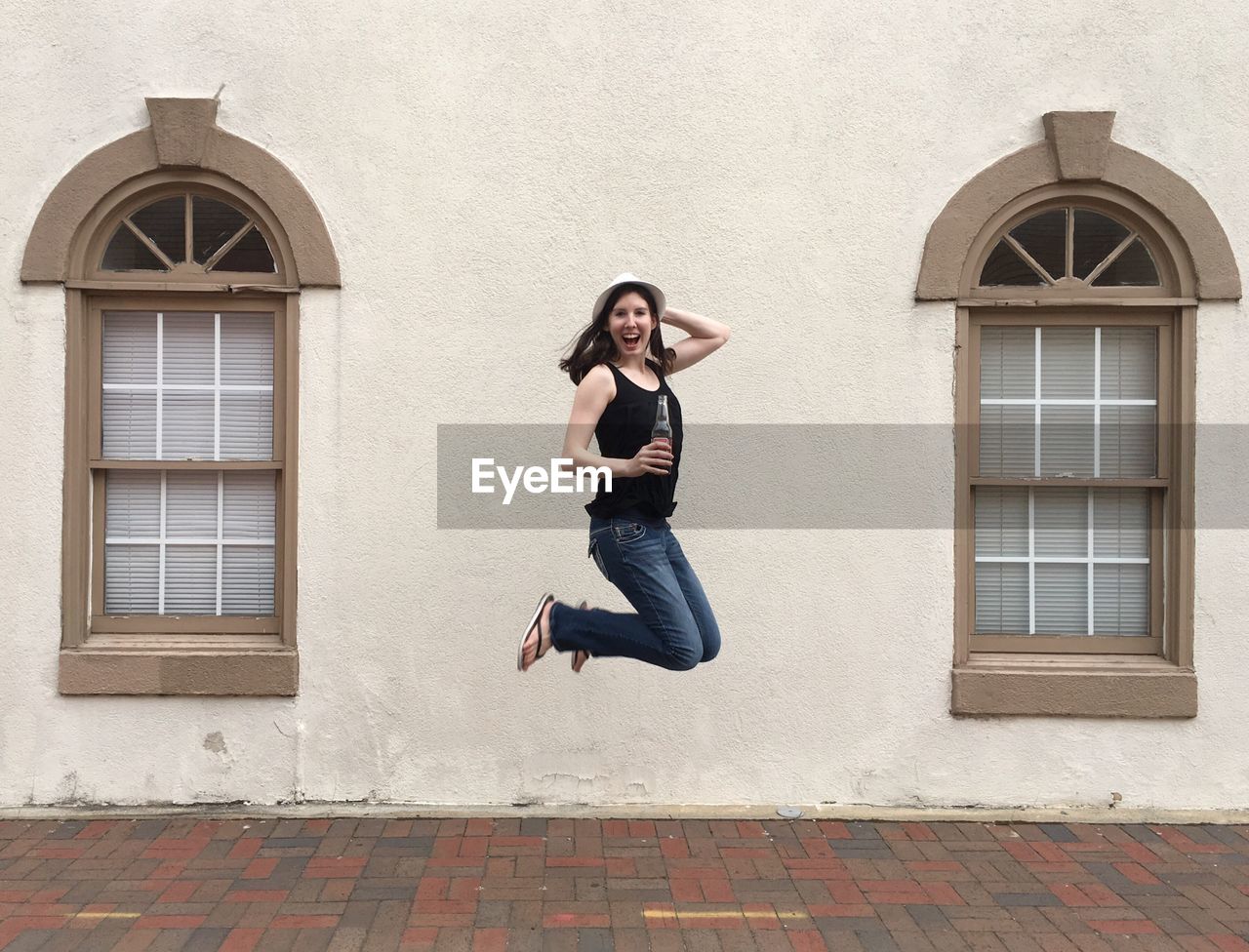 Portrait of happy woman jumping against wall