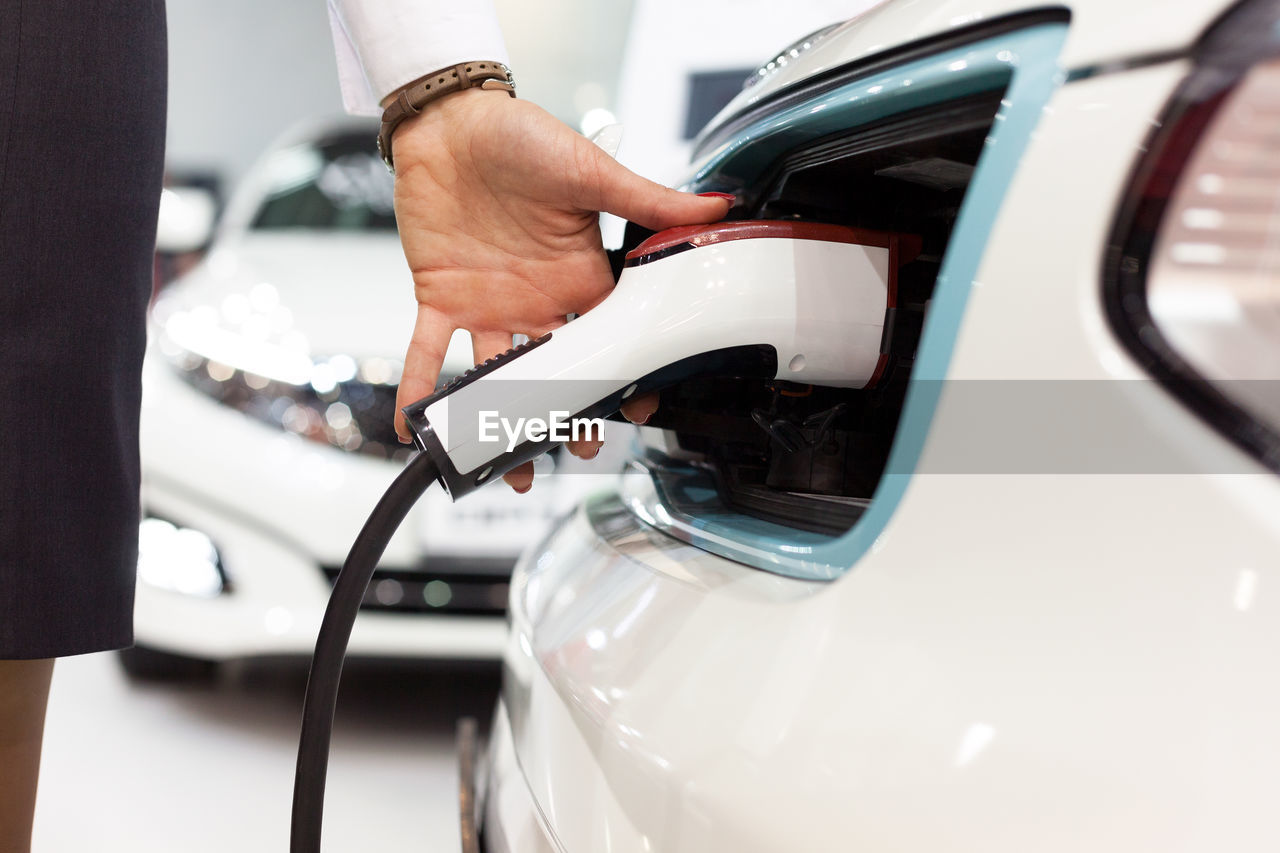 Cropped hand of woman filling fuel in car