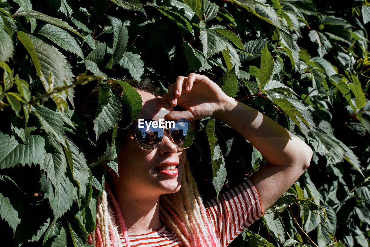 Young woman wearing sunglasses amidst plants