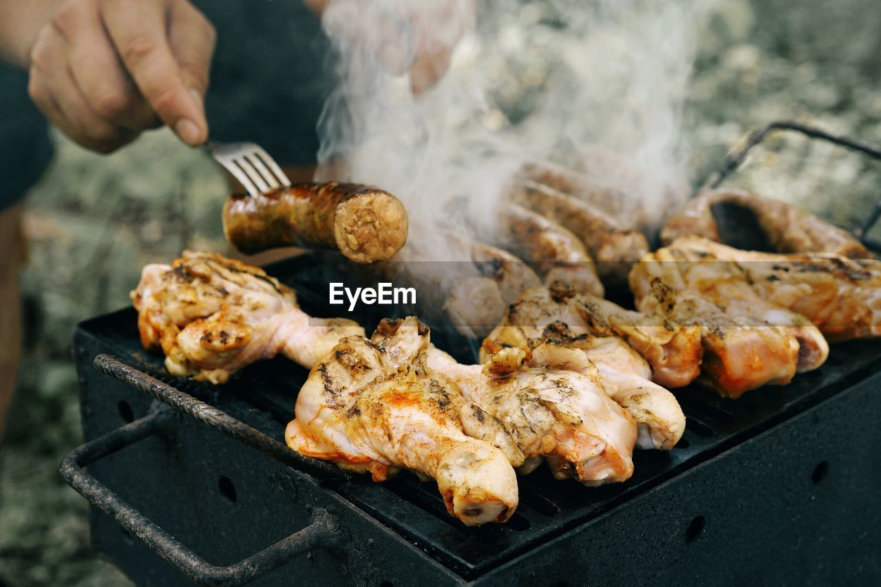 Cropped image of man grilling meat on barbecue grill