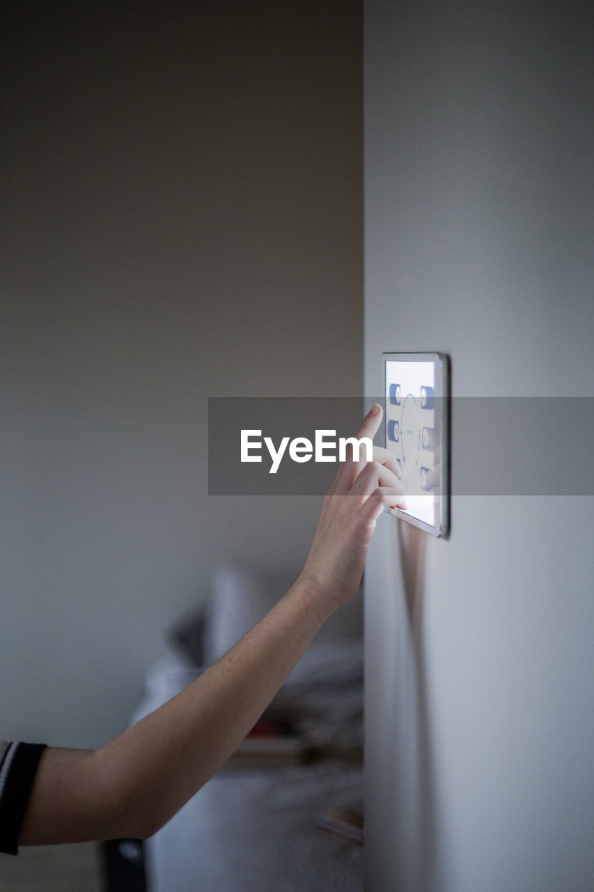 Cropped image of boy using digital tablet mounted on wall at home