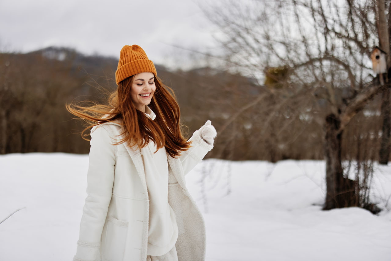 young woman standing on snow covered field during winter