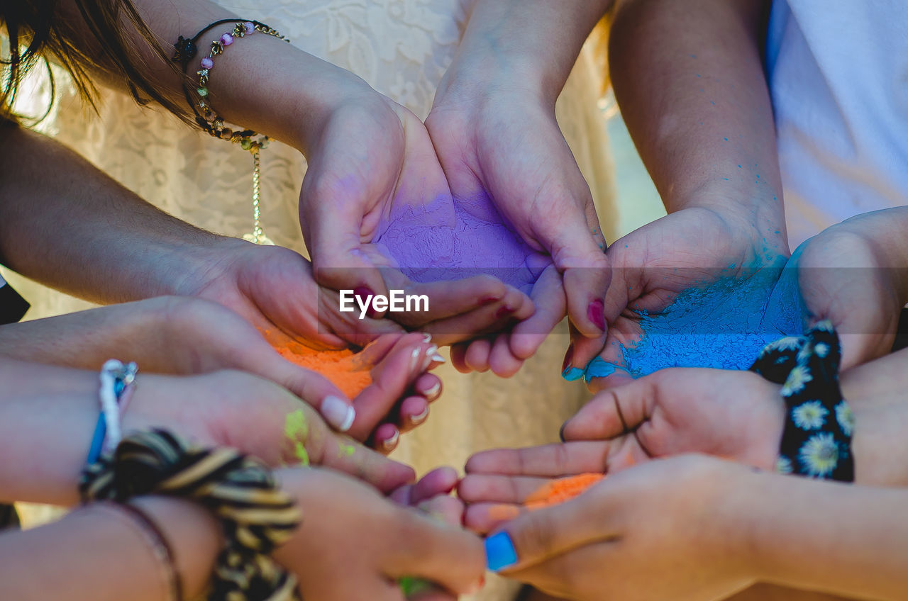 High angle view of people hands holding multi colored powder paint