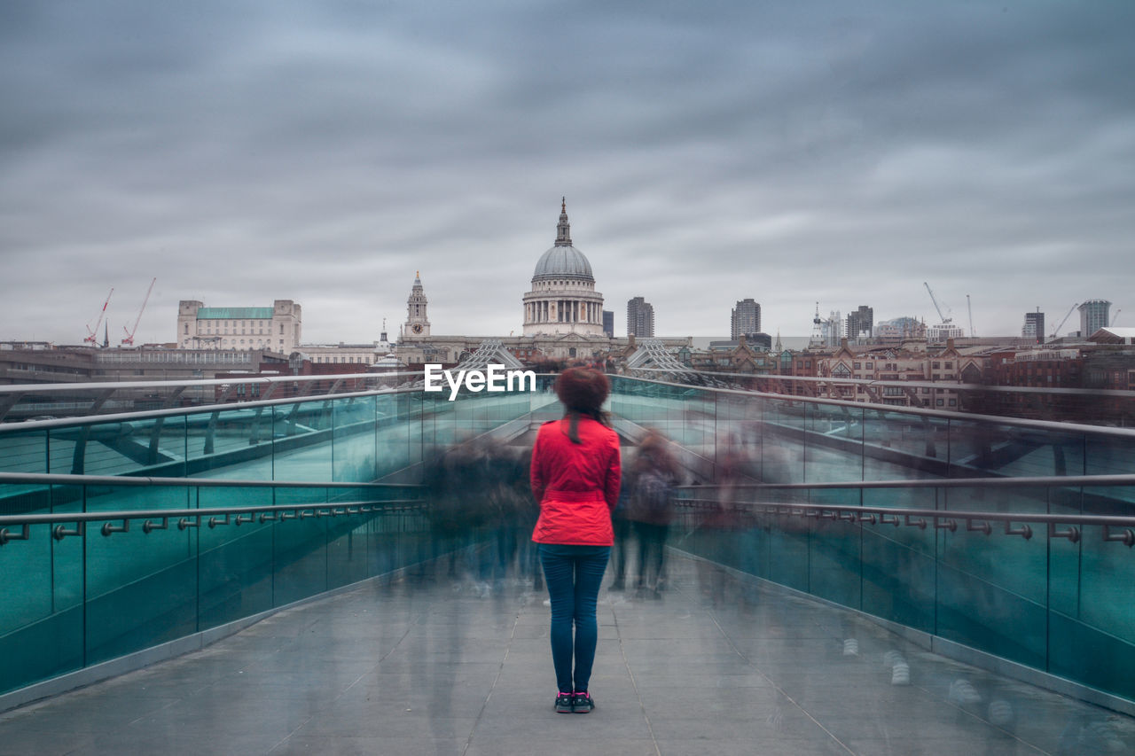 Woman standing on millennium bridge looking at st paul cathedral against sky