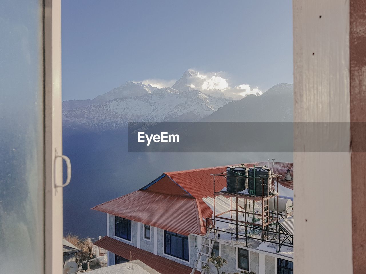 Houses by mountain against sky during winter