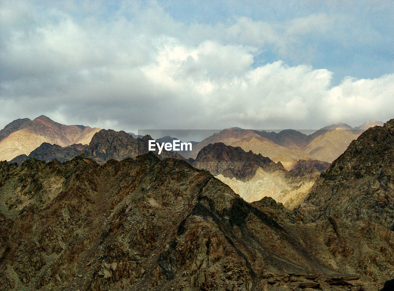 Scenic view of rocky mountains against cloudy sky