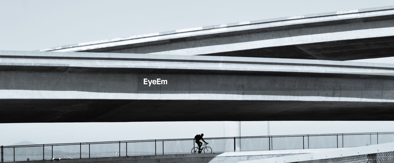 Low angle view of cyclist on bridge against sky