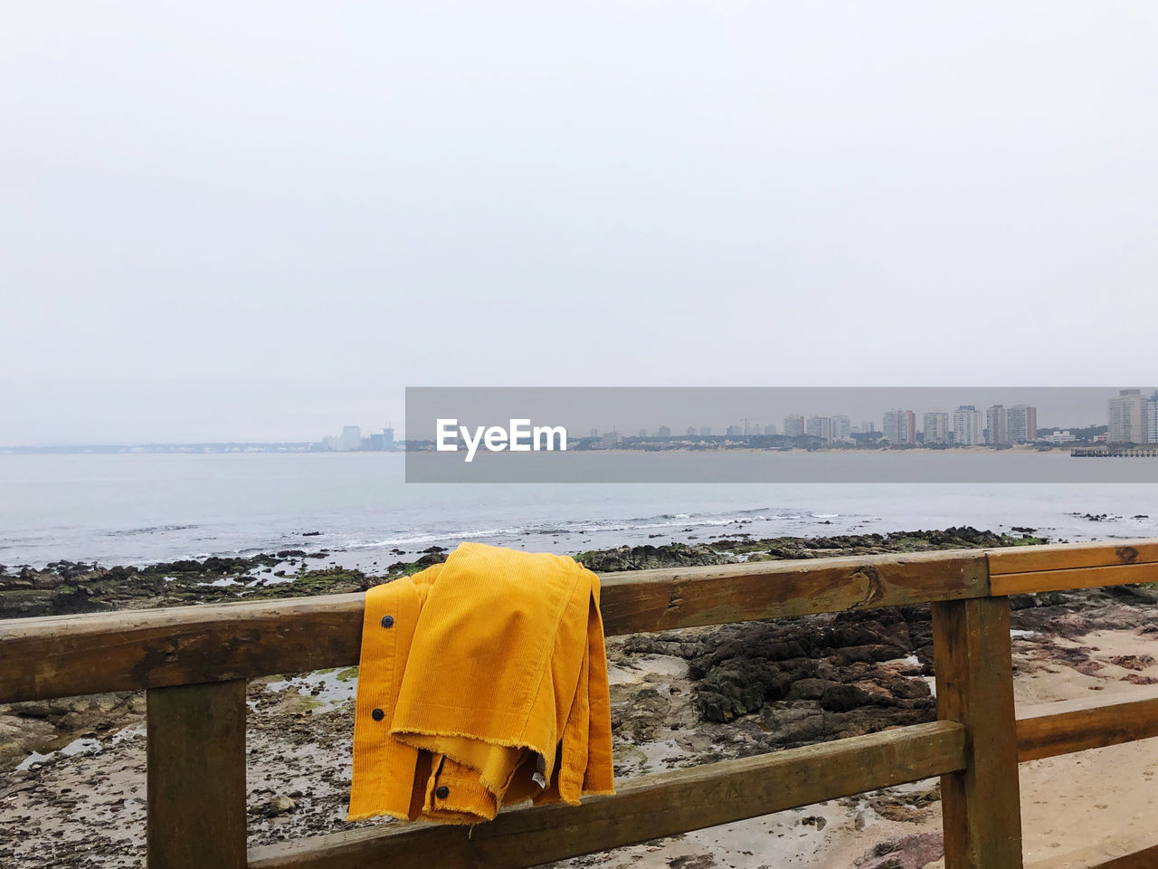 Jacket on railing at beach against clear sky