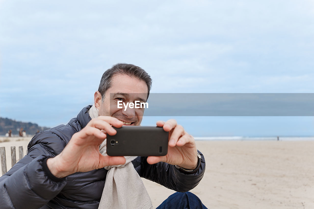 PORTRAIT OF MAN PHOTOGRAPHING ON BEACH