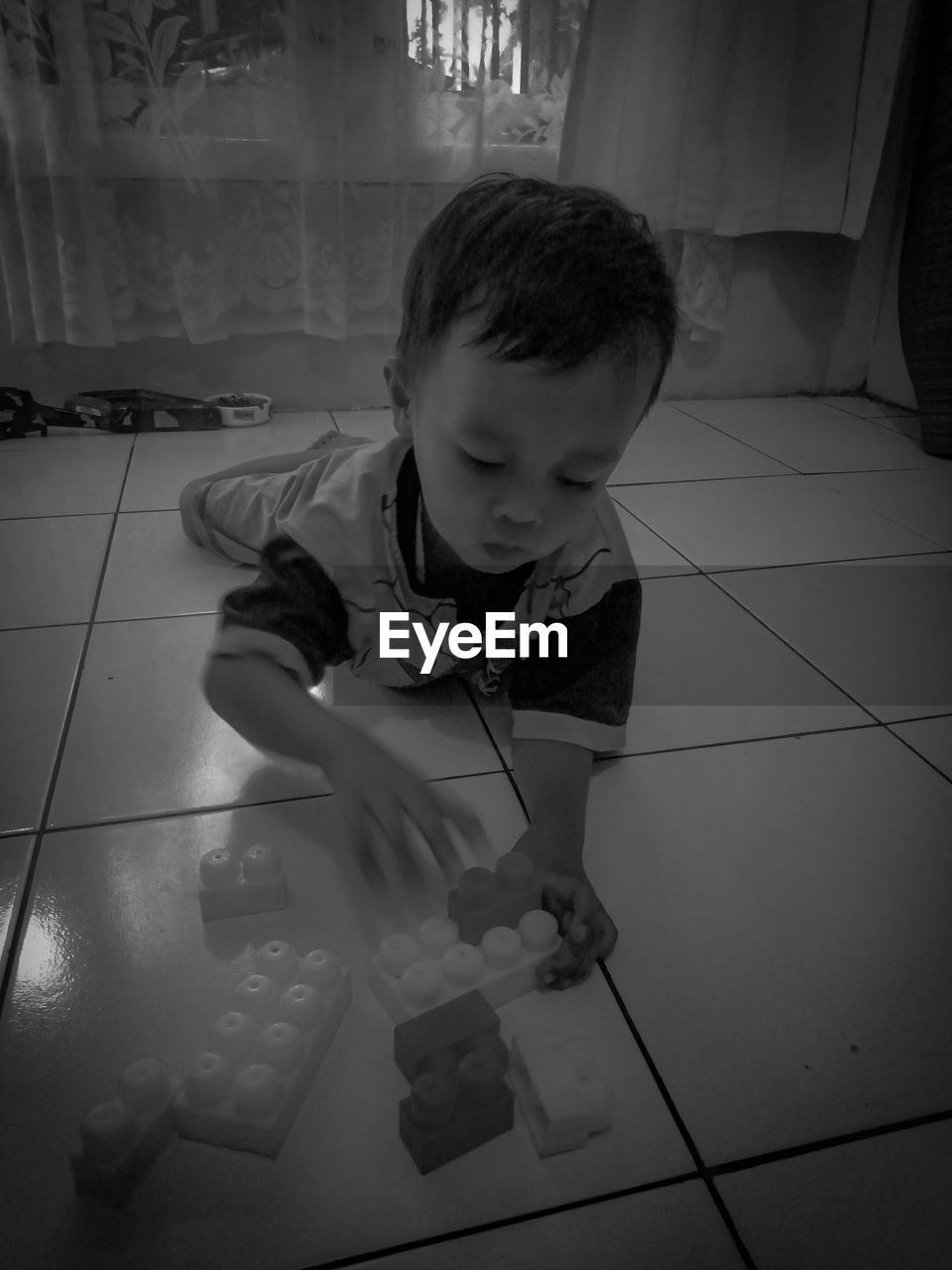 HIGH ANGLE VIEW OF BOY LOOKING AT CAMERA AT HOME