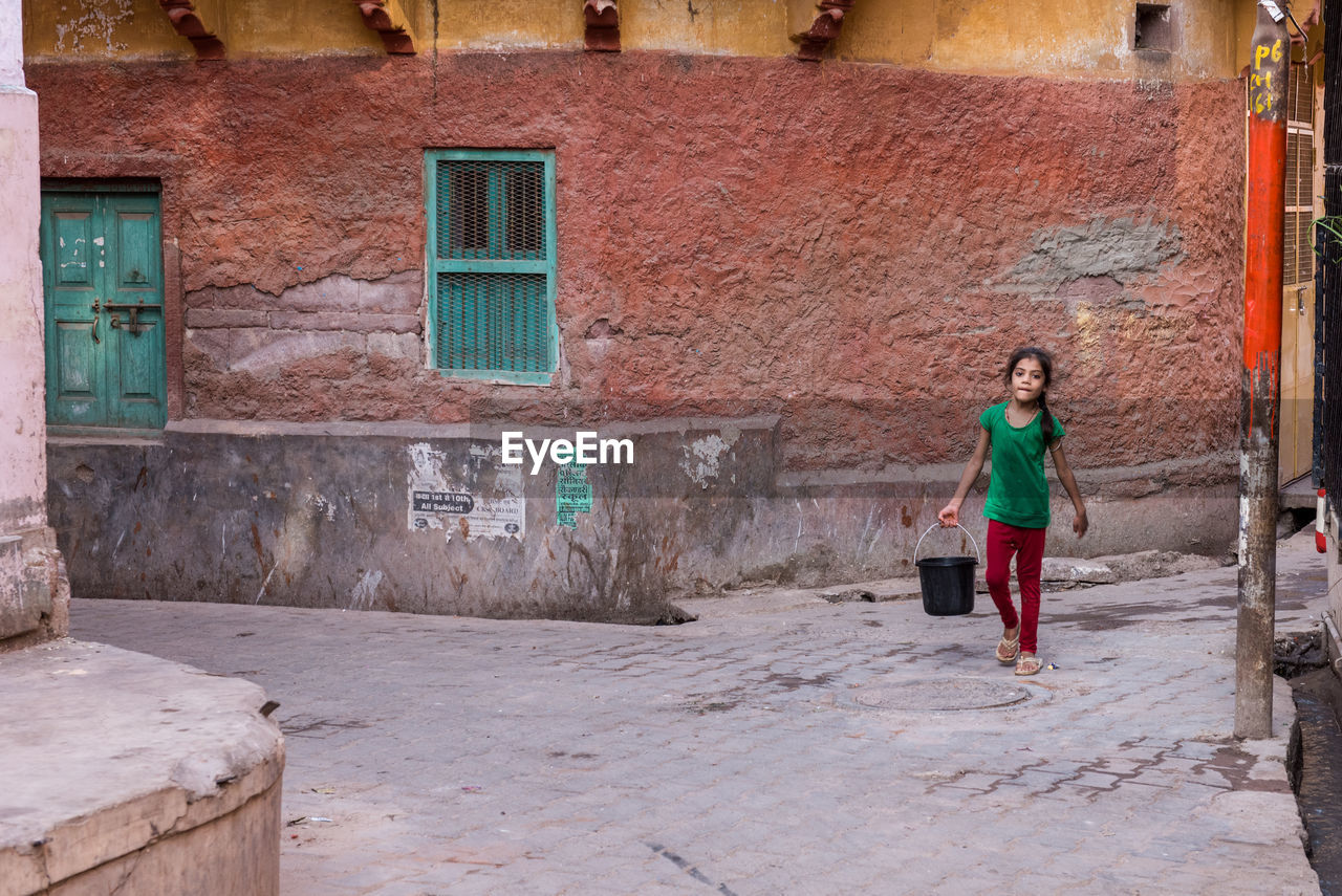 FULL LENGTH OF WOMAN STANDING ON BUILDING