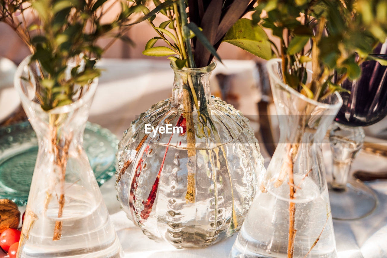 High angle of transparent glass vases with bunches of fresh flowers placed on table for event