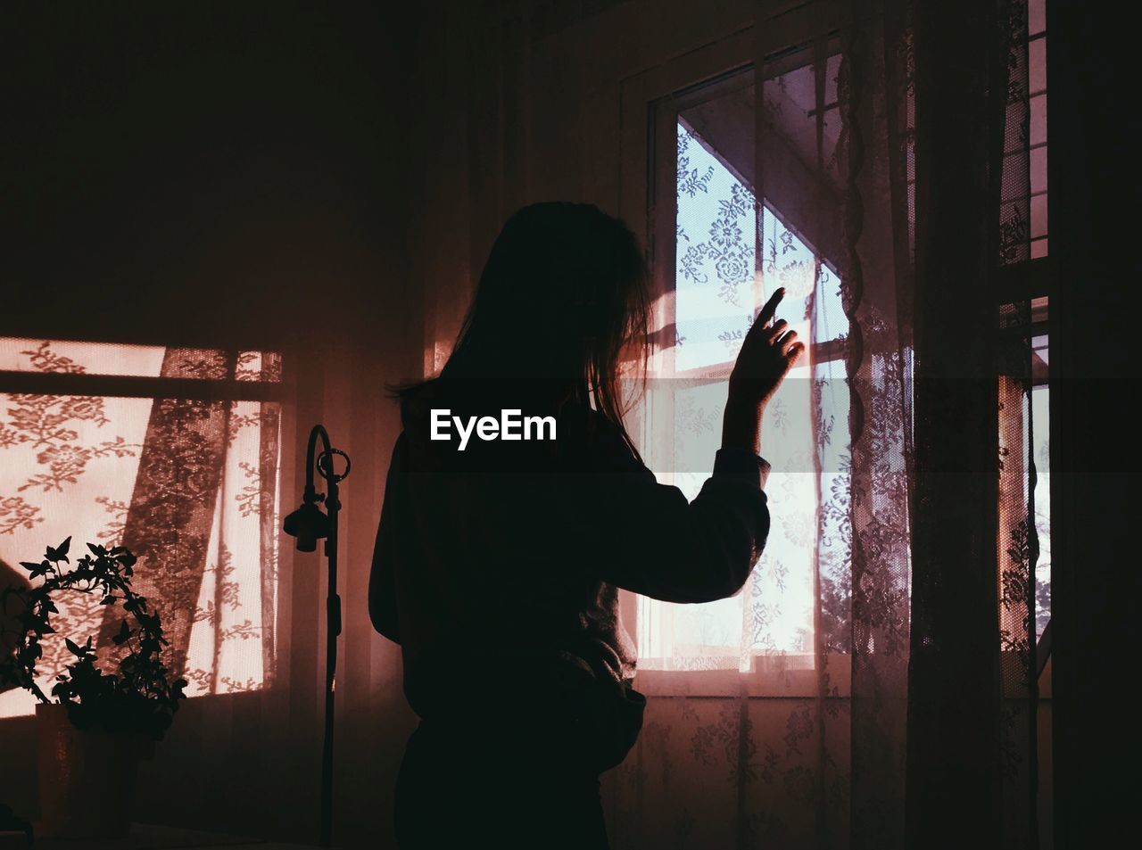 Woman looking through window at home