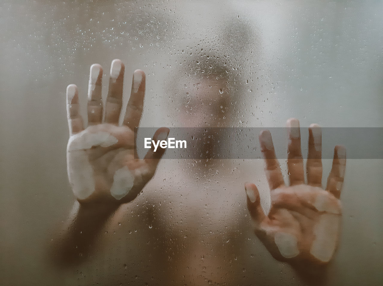 Close-up of hand touching wet glass window