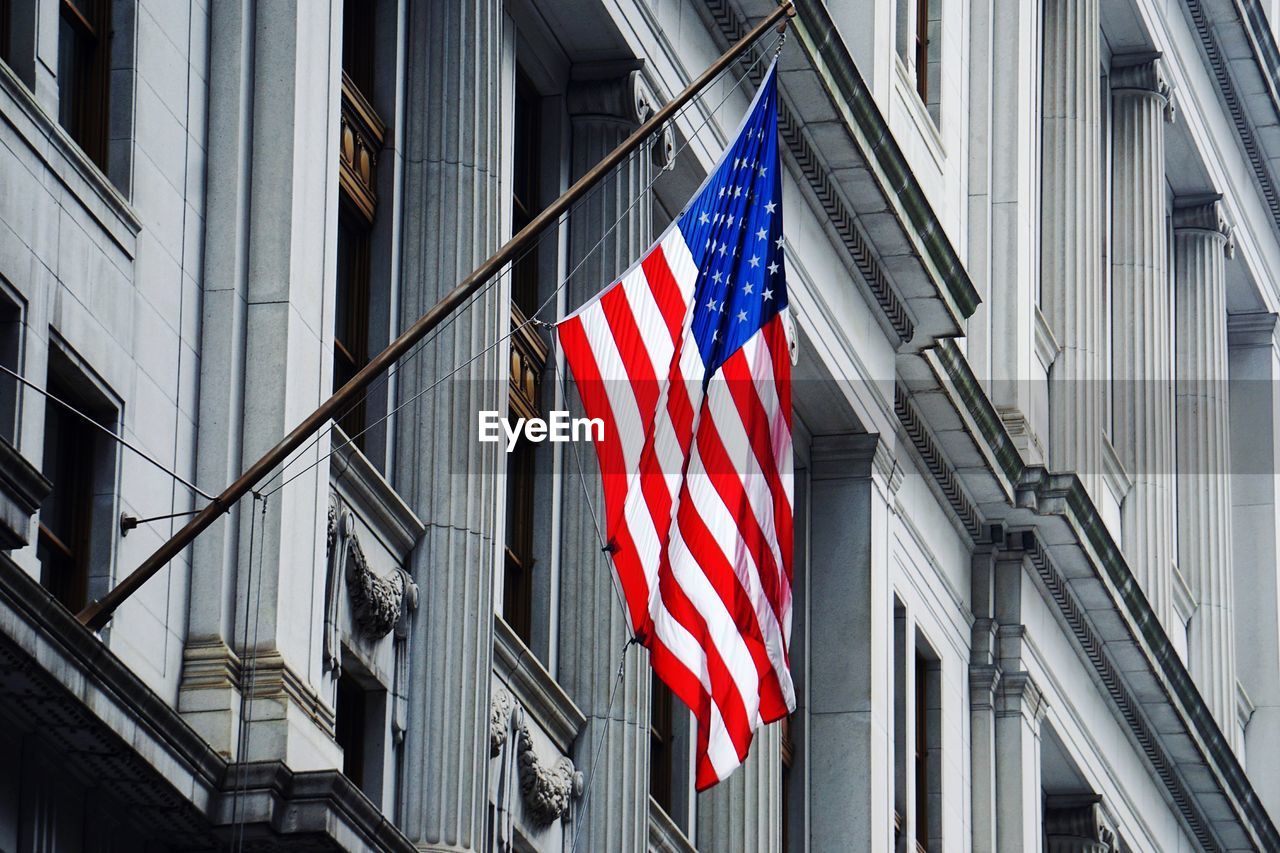 Low angle view of american flag against building in city