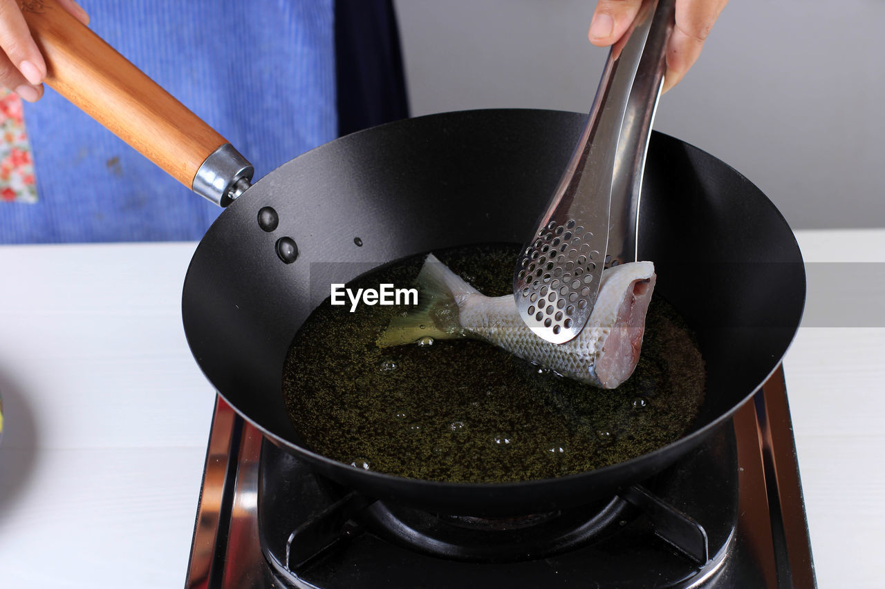 cropped hand of woman holding cooking pan